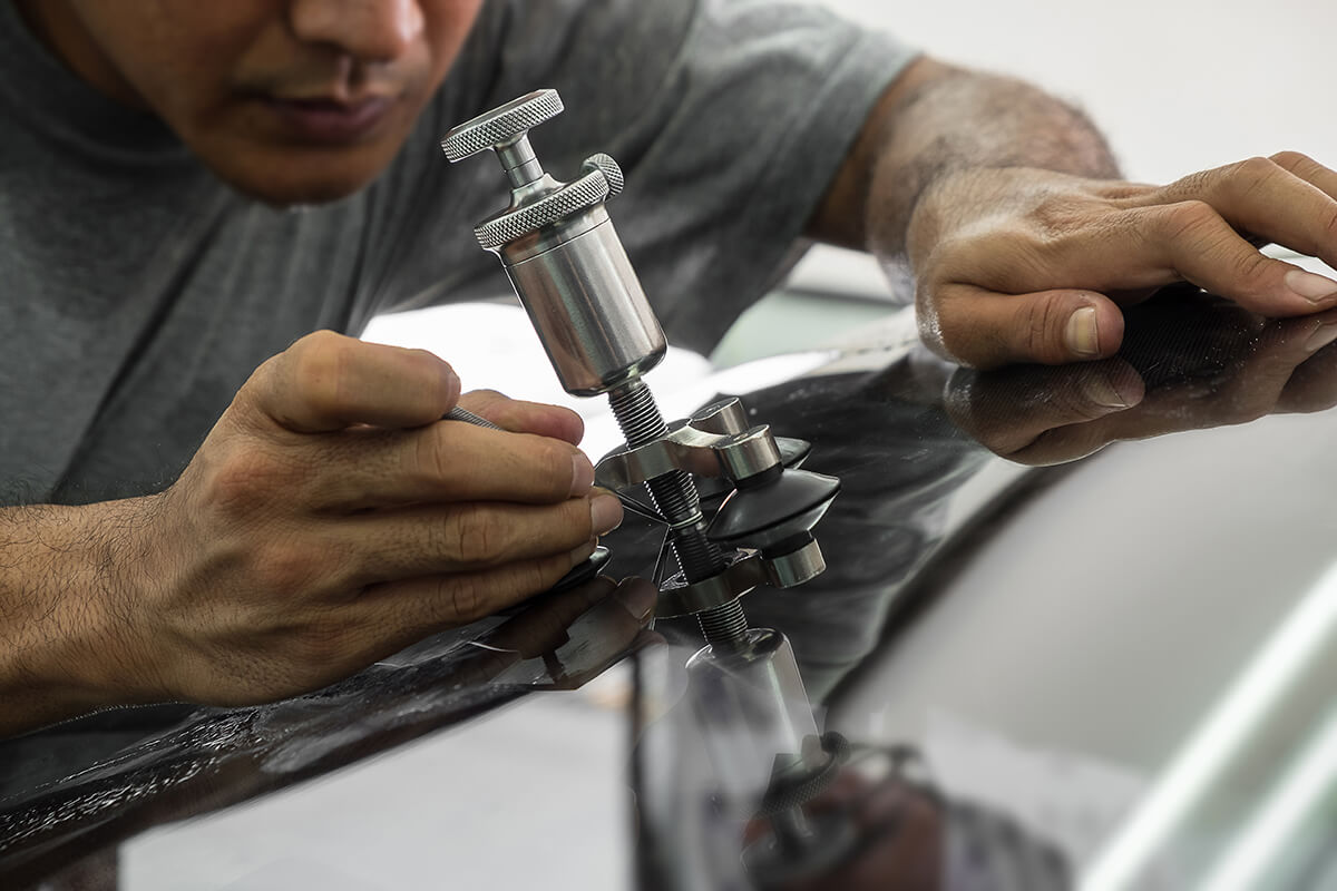 A man using repairing equipment to fix damaged windshield